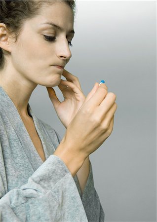 puckered lips profile - Woman wearing bathrobe, holding up pill, making face Stock Photo - Premium Royalty-Free, Code: 695-05764372