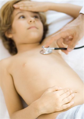 stomach pain - Doctor holding stethoscope to boy's chest Stock Photo - Premium Royalty-Free, Code: 695-05764389