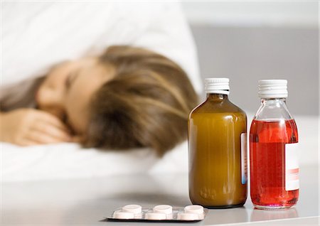 pill bottles girl - Girl lying in bed, medicines by bed side in foreground Stock Photo - Premium Royalty-Free, Code: 695-05764393