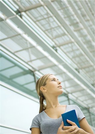 Woman holding agenda, structure in background, low angle view Stock Photo - Premium Royalty-Free, Code: 695-05764415