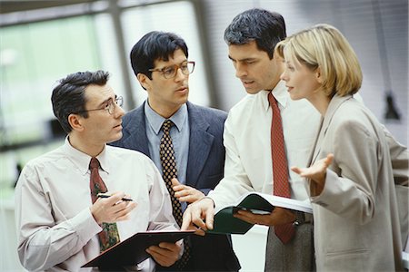 simsearch:649-07436826,k - Four business colleagues standing discussing document and agenda Stock Photo - Premium Royalty-Free, Code: 695-05764475