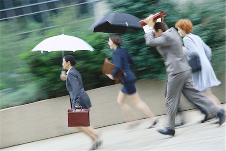 rain businesswoman - Group of business executives hurrying through rain Stock Photo - Premium Royalty-Free, Code: 695-05764578