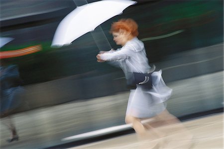 Businesswoman hurrying with umbrella Stock Photo - Premium Royalty-Free, Code: 695-05764596