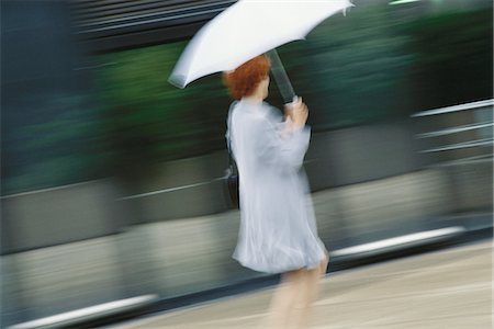 Businesswoman hurrying with umbrella Stock Photo - Premium Royalty-Free, Code: 695-05764597