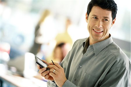 Man using electronic organizer, smiling Foto de stock - Sin royalties Premium, Código: 695-05764761