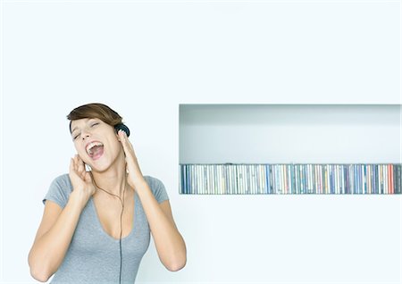 song white background - Young woman listening to headphones and singing, next to row of CDs, eyes closed Stock Photo - Premium Royalty-Free, Code: 695-05764815