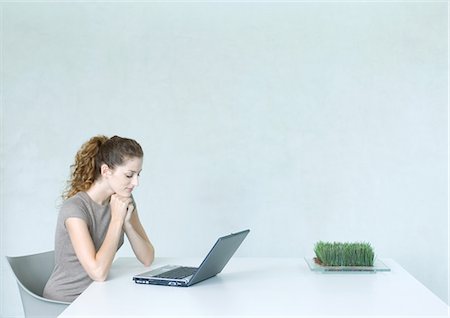 Woman using laptop, tray of wheatgrass on table Foto de stock - Sin royalties Premium, Código: 695-05764823