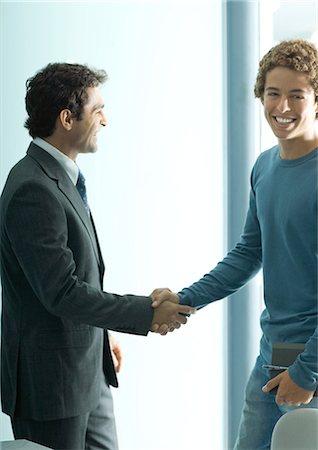 Businessman and casually dressed young man shaking hands Stock Photo - Premium Royalty-Free, Code: 695-05764834
