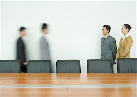 Business executives standing, facing associates arriving in conference room Stock Photo - Premium Royalty-Free, Code: 695-05764936
