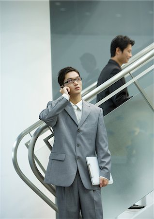 person on phone with clipboard - Businessman using cell phone near staircase Stock Photo - Premium Royalty-Free, Code: 695-05764945