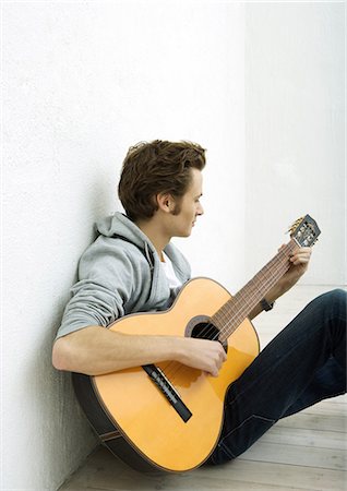 simsearch:400-04943773,k - Young man sitting on floor, playing guitar Foto de stock - Royalty Free Premium, Número: 695-05764989