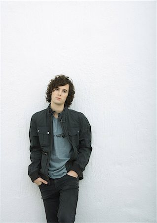 Young man leaning against wall with hands in pockets, portrait, white background Foto de stock - Sin royalties Premium, Código: 695-05765017