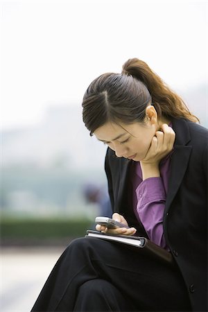 Businesswoman using messaging phone, leaning forward Stock Photo - Premium Royalty-Free, Code: 695-05765064