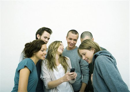 Group of young adult and teenage friends looking at cell phone, white background Stock Photo - Premium Royalty-Free, Code: 695-05765117