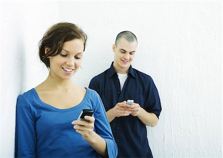 Young man and young woman using cell phones Stock Photo - Premium Royalty-Free, Code: 695-05765128