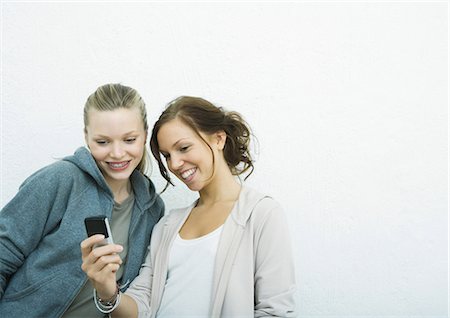 Young female friends looking at cell phone together Stock Photo - Premium Royalty-Free, Code: 695-05765133