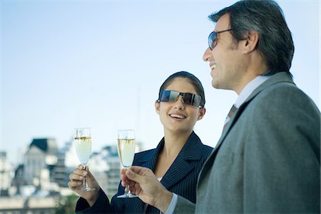 Business partners holding up glasses of champagne, skyline in background Stock Photo - Premium Royalty-Free, Code: 695-05765194