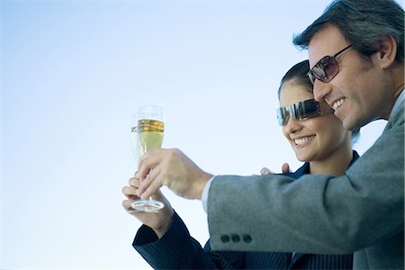 Man and woman clinking glasses of champagne, sky in background Stock Photo - Premium Royalty-Free, Code: 695-05765196