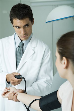 Doctor taking woman's blood pressure Stock Photo - Premium Royalty-Free, Code: 695-05765434