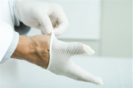 Doctor putting on latex gloves, close-up Foto de stock - Sin royalties Premium, Código: 695-05765443