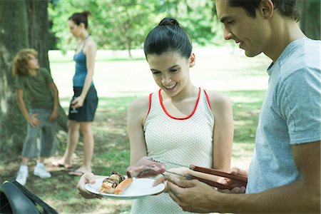 Man serving teen girl grilled meats from barbecue Stock Photo - Premium Royalty-Free, Code: 695-05765592