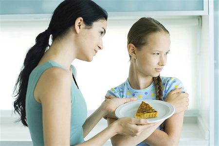 Girl turning head from woman holding piece of quiche Stock Photo - Premium Royalty-Free, Code: 695-05765620
