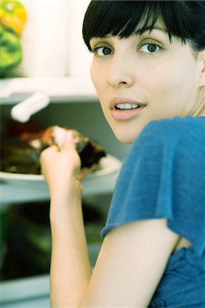 simsearch:695-05779160,k - Woman taking piece of cake from refrigerator, looking over shoulder at camera Stock Photo - Premium Royalty-Free, Code: 695-05765649