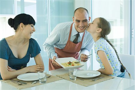 Homme qui dessert spaghetti femme et sa fille, jeune fille embrassant le père sur la joue Photographie de stock - Premium Libres de Droits, Code: 695-05765643