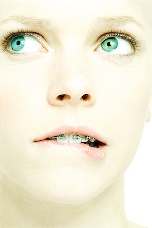 Teenage girl with braces biting lip, extreme close-up Fotografie stock - Premium Royalty-Free, Codice: 695-05765668