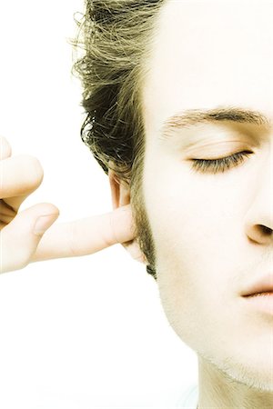plugging ears - Young man plugging ear, eyes closed Stock Photo - Premium Royalty-Free, Code: 695-05765721