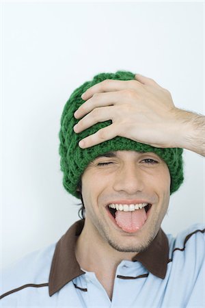 eccentric hat - Young man holding head and sticking out tongue, portrait Stock Photo - Premium Royalty-Free, Code: 695-05765899