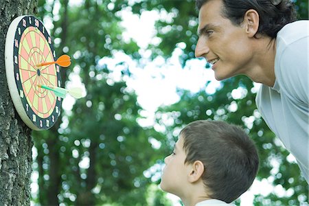 dart board photography - Boy and father looking at dartboard on tree Stock Photo - Premium Royalty-Free, Code: 695-05765911