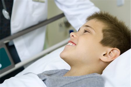 doctor patient bed side view - Child lying in hospital bed, doctor standing by side Stock Photo - Premium Royalty-Free, Code: 695-05765957