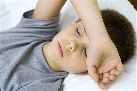 person in hospital bed overhead - Boy lying down with arm covering forehead Stock Photo - Premium Royalty-Free, Code: 695-05765959