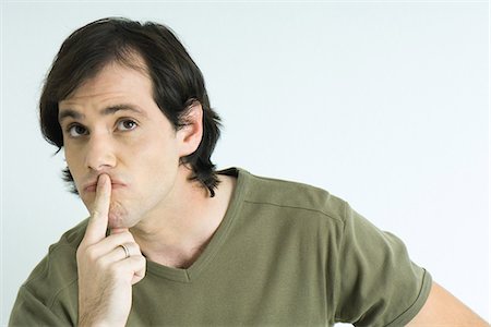 simsearch:693-06435766,k - Man with finger over lips, looking up, raising eyebrows, portrait Stock Photo - Premium Royalty-Free, Code: 695-05766162