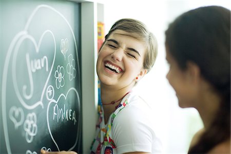 Young female friends writing names in hearts on chalkboard, laughing Stock Photo - Premium Royalty-Free, Code: 695-05766237