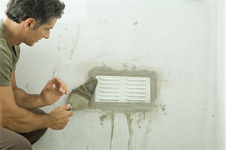 Man applying plaster around air vent Stock Photo - Premium Royalty-Free, Code: 695-05766314