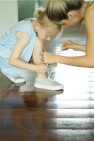 Mother helping little girl tie shoe laces Stock Photo - Premium Royalty-Free, Code: 695-05766368