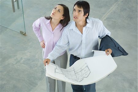 sell home - Young couple holding blueprints, looking up, high angle view Stock Photo - Premium Royalty-Free, Code: 695-05766464