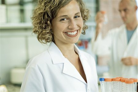 Female lab worker holding rack of empty test tubes, smiling at camera, portrait Stock Photo - Premium Royalty-Free, Code: 695-05766497