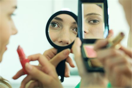 putting on lipstick - Two young friends looking at selves in hand mirrors, holding lipstick, cropped view Stock Photo - Premium Royalty-Free, Code: 695-05766501
