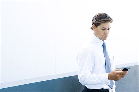 Young businessman looking at cell phone, waist up Stock Photo - Premium Royalty-Free, Code: 695-05766547