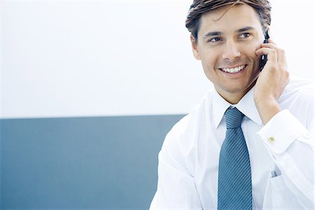 dimpled - Young businessman using cell phone, smiling, looking away Stock Photo - Premium Royalty-Free, Code: 695-05766550