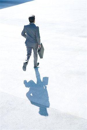 shadow silhouette man - Young businessman running outdoors, carrying briefcase, full length, rear view Stock Photo - Premium Royalty-Free, Code: 695-05766575