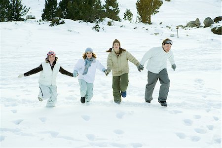 Four young friends running together in snow, holding hands, full length Foto de stock - Sin royalties Premium, Código: 695-05766594