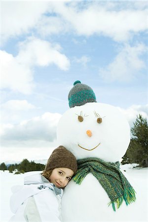 female snowman pictures - Girl leaning against snowman, smiling at camera, portrait Stock Photo - Premium Royalty-Free, Code: 695-05766595