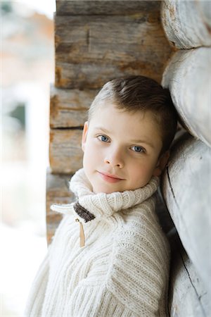 Boy leaning against wood cabin, smiling at camera Foto de stock - Sin royalties Premium, Código: 695-05766609