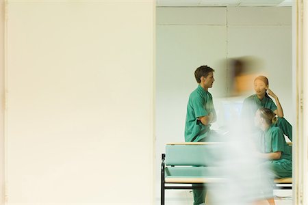 Medical workers chatting in office, adult walking past doorway, blurred motion Foto de stock - Sin royalties Premium, Código: 695-05766648