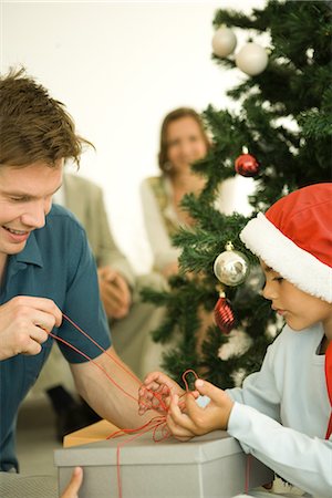 Father and son opening present together by Christmas tree Stock Photo - Premium Royalty-Free, Code: 695-05766707
