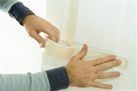 Man putting masking tape on door woodwork, close-up of hands Stock Photo - Premium Royalty-Free, Code: 695-05766789